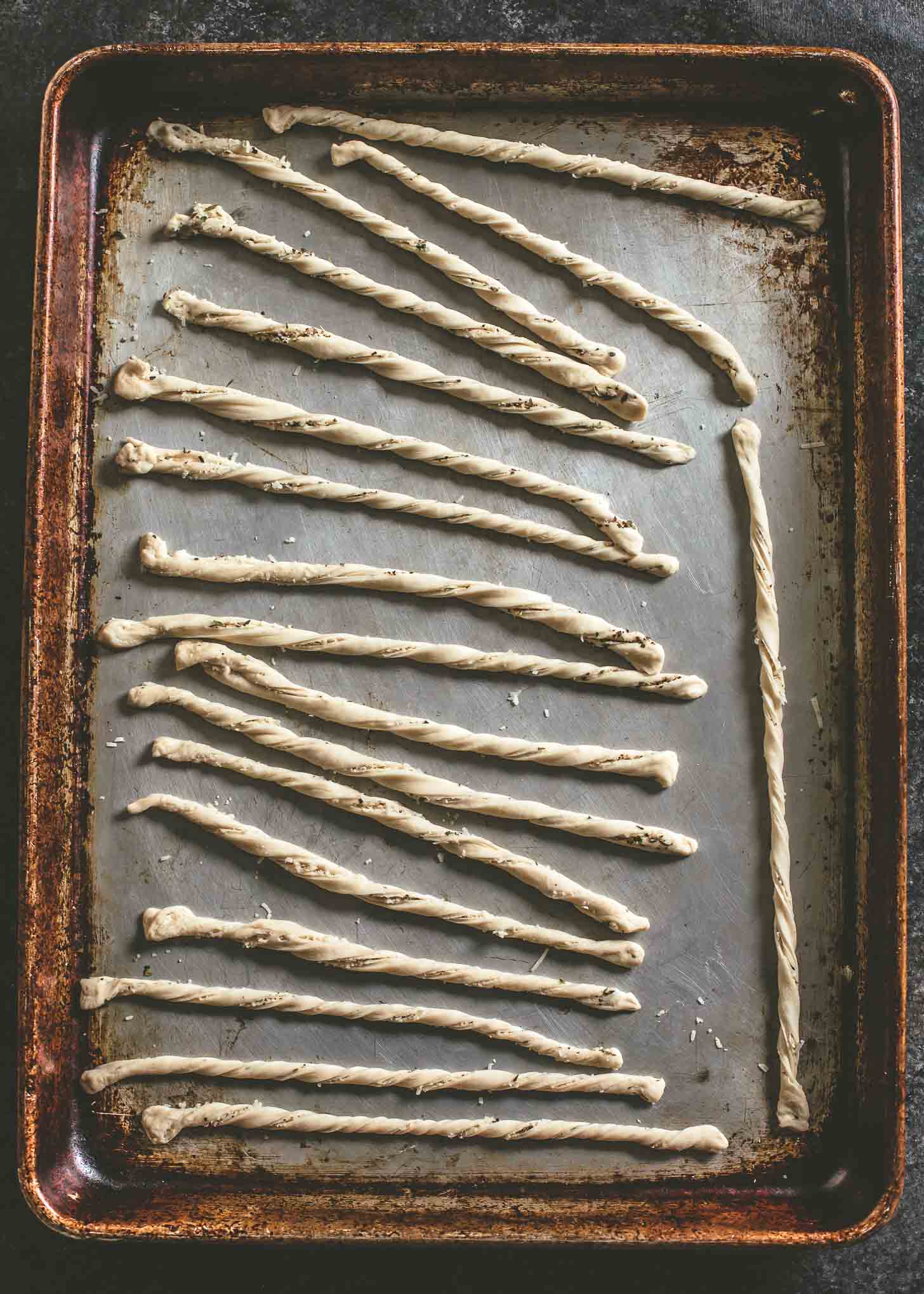 overhead image of uncooked breadsticks on a sheet pan