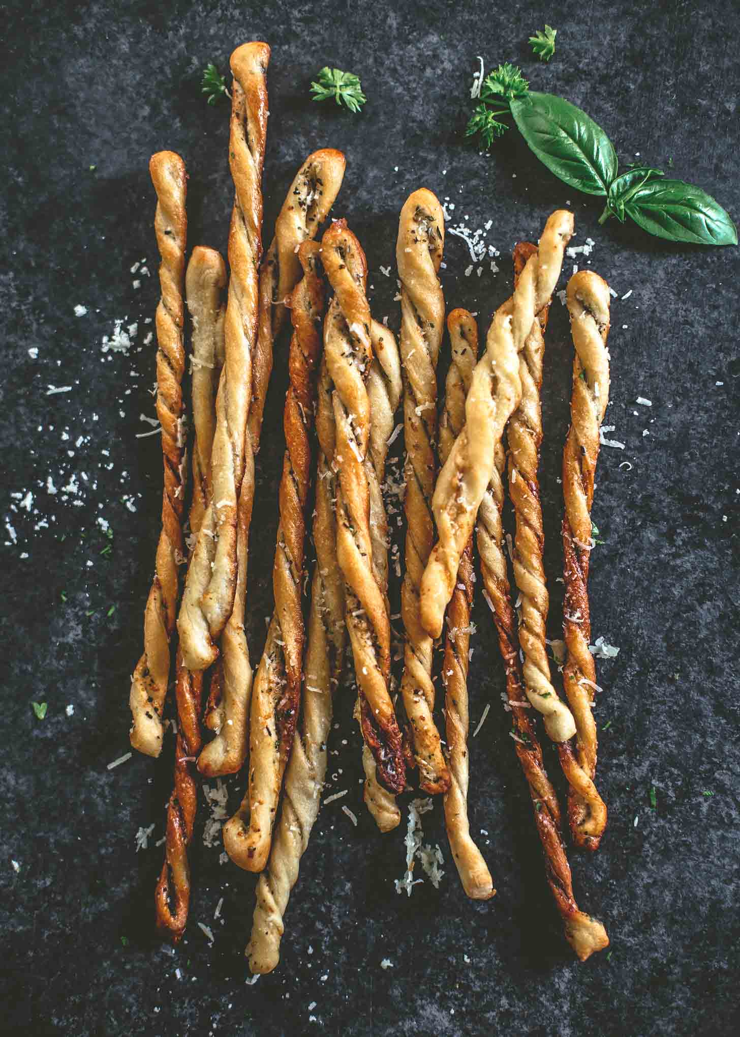 overhead image of baked breadsticks on a grey countertop