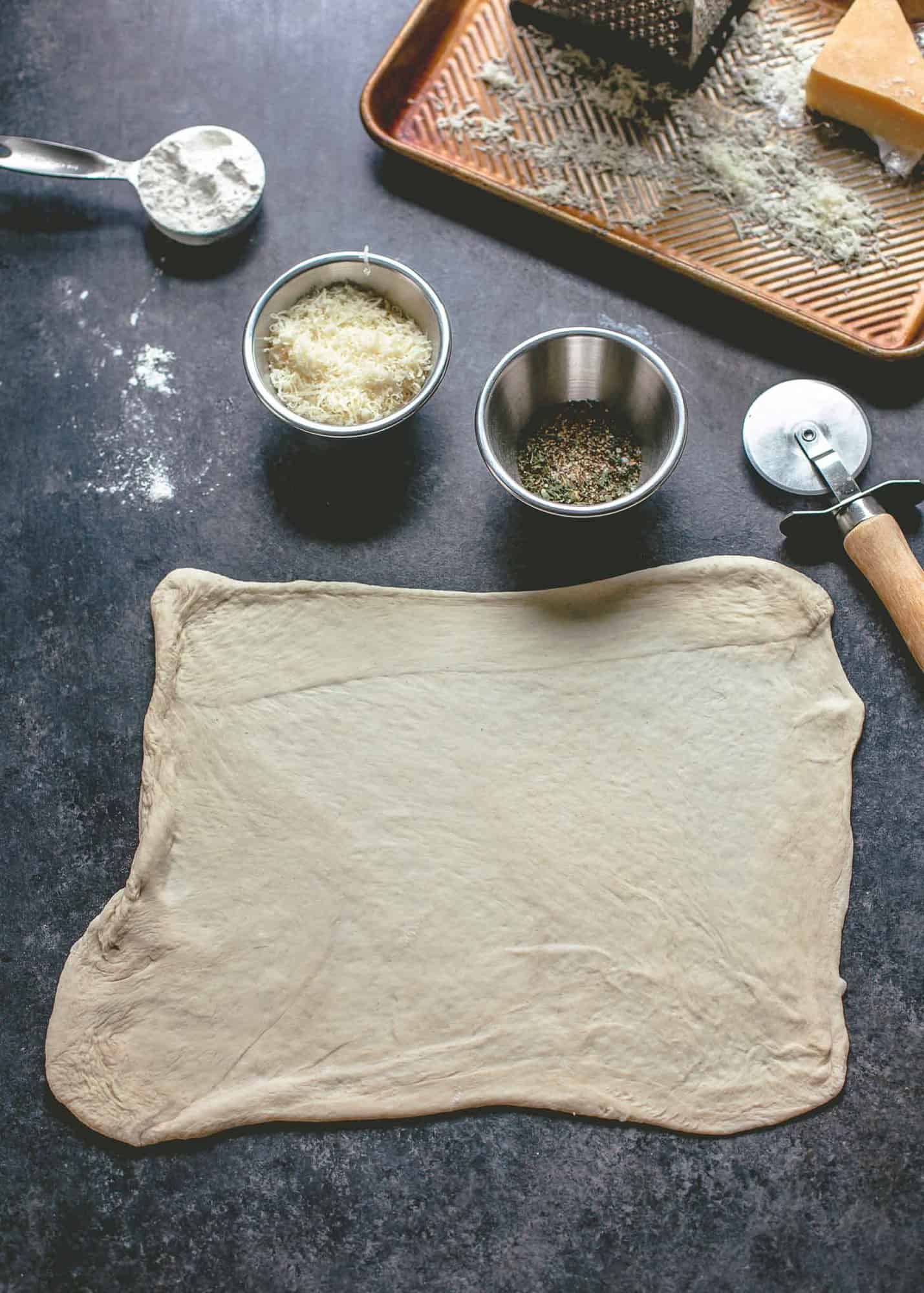 overhead image of pizza dough spread into a square