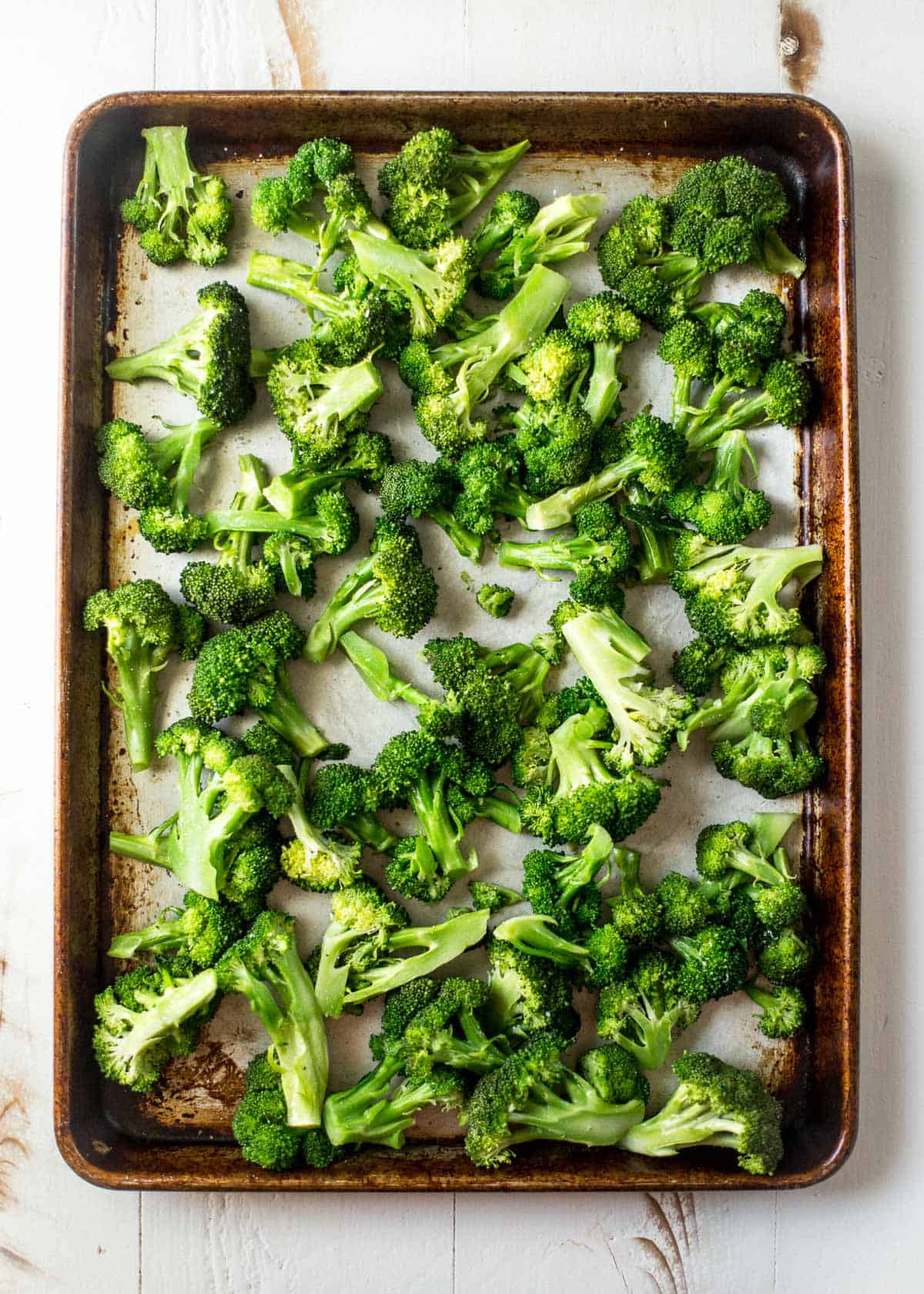 overhead image of raw broccoli on a sheet pan