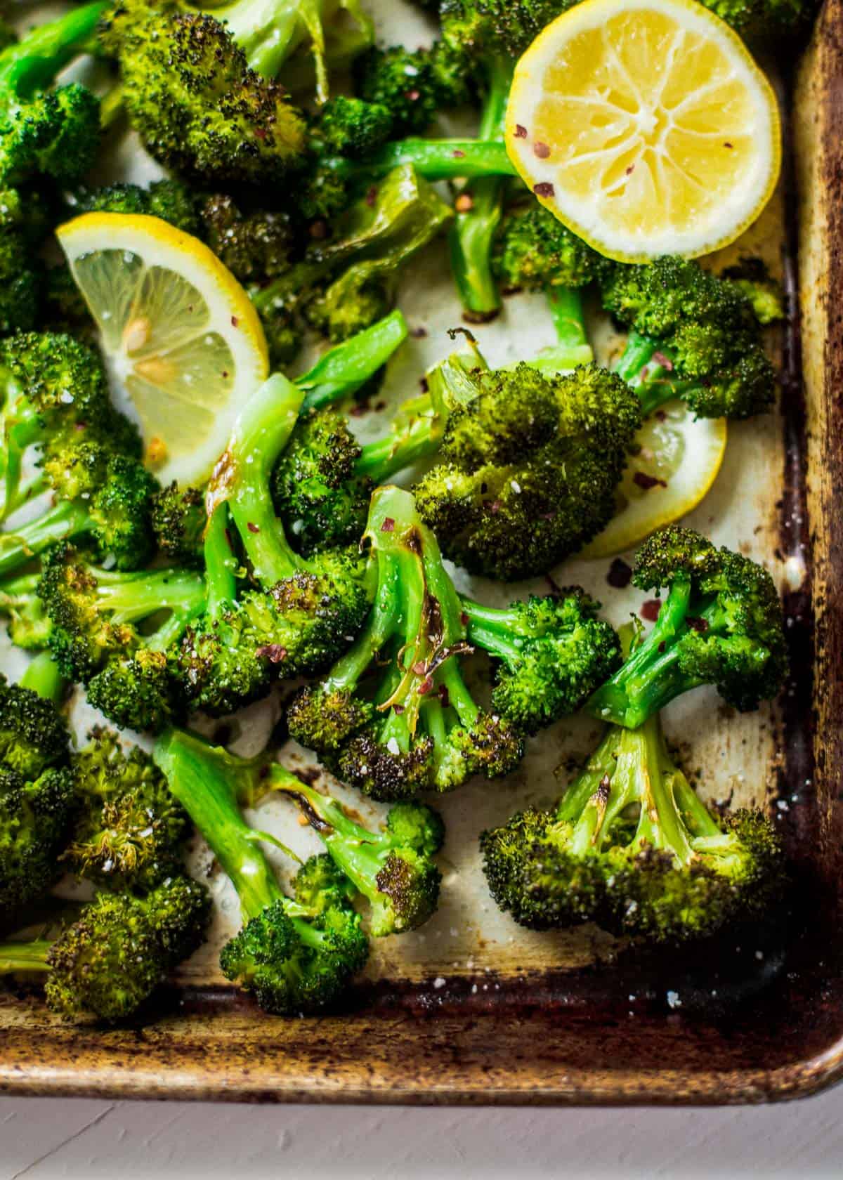 overhead image of roasted broccoli and lemon slices on a sheet pan