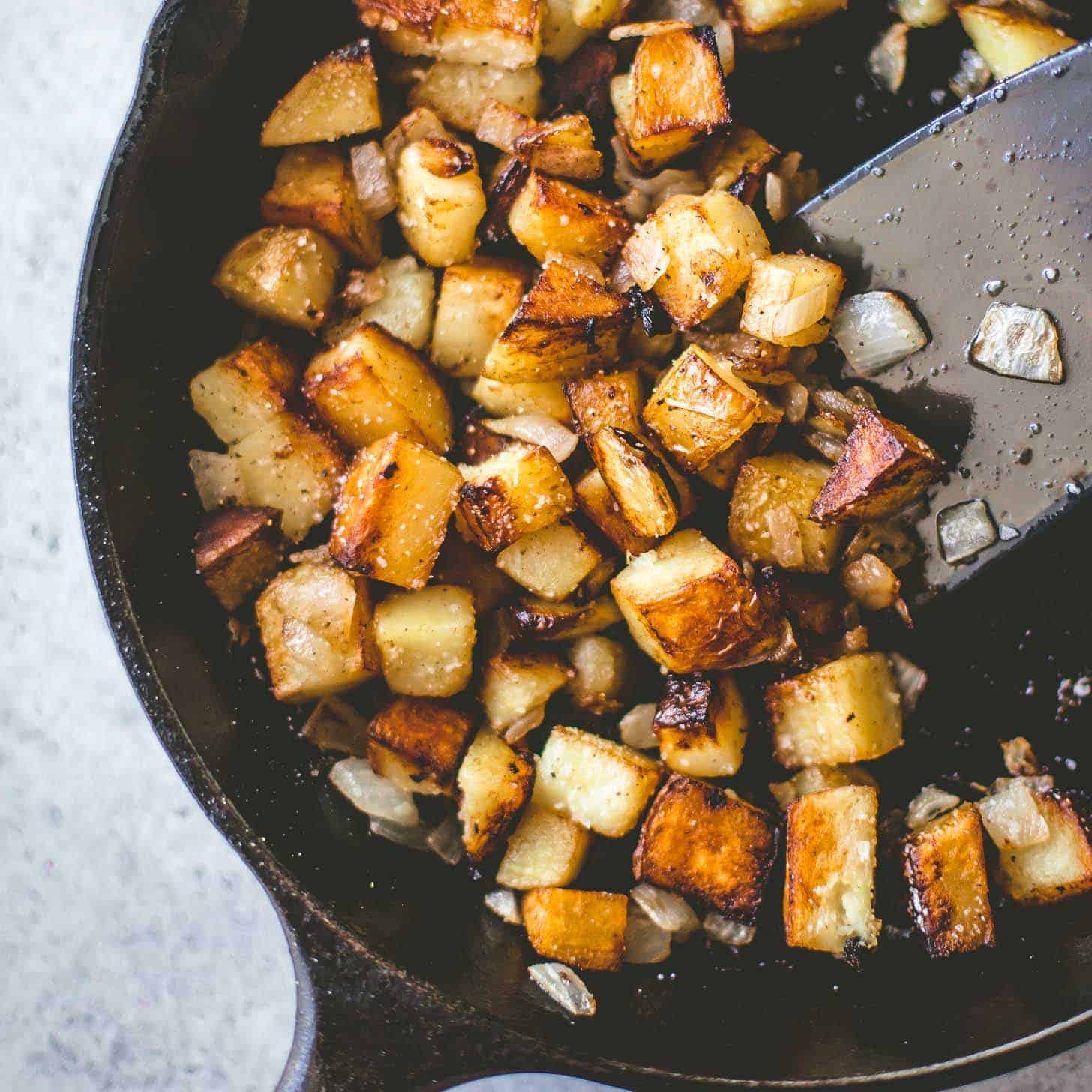 stirring home fries in a skillet