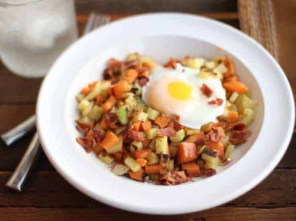 Sweet Potato, Apple and Bacon Hash in a white bowl topped with a fried egg