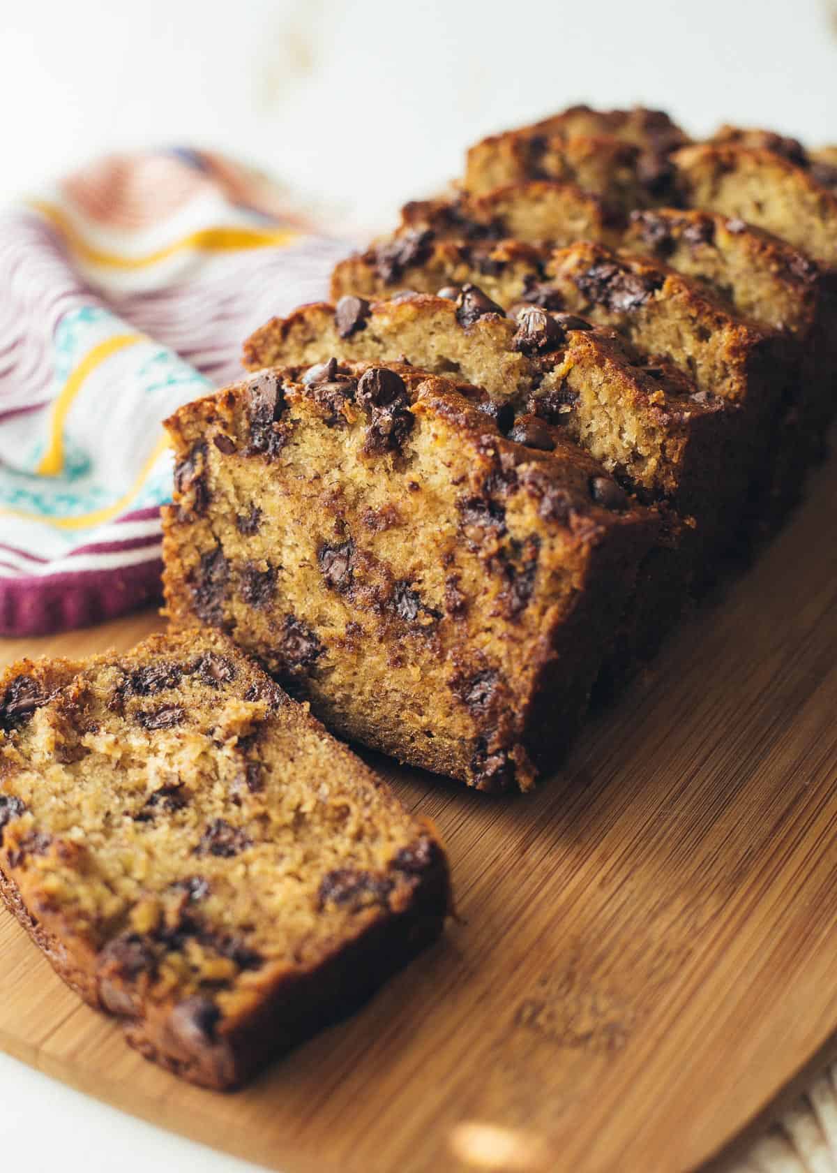 banana bread slices slices with chocolate chips on a wooden cutting board