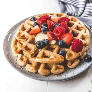 waffle with fruit and syrup on a grey plate