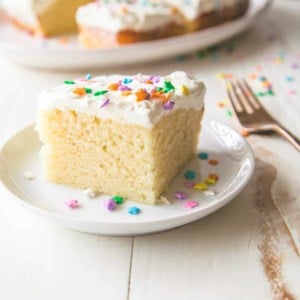 vanilla cake with white frosting and sprinkles on a plate with a fork