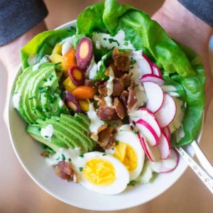 cobb salad in a bowl being held by hands