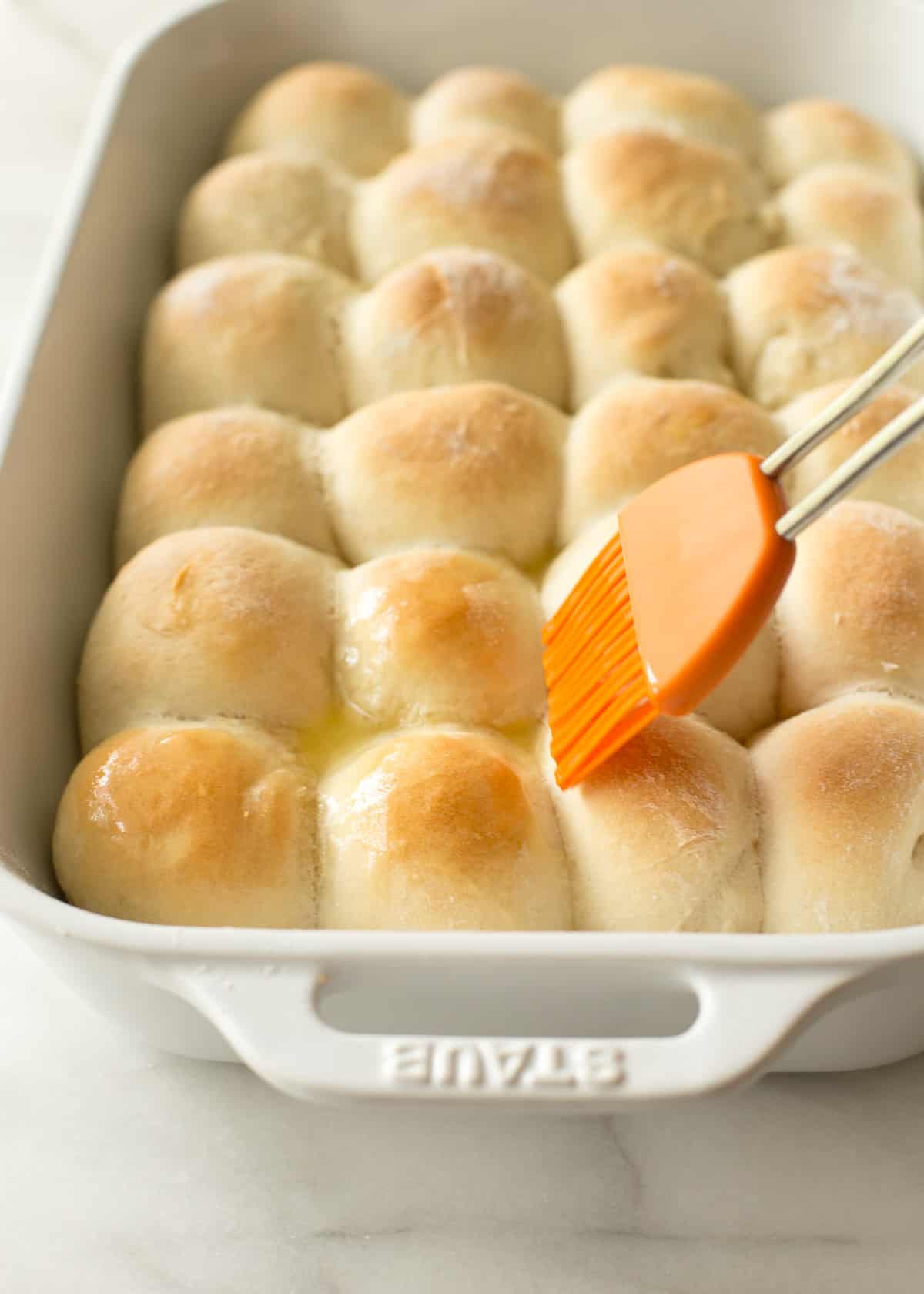 brushing butter on dinner rolls with a silicon basting brush