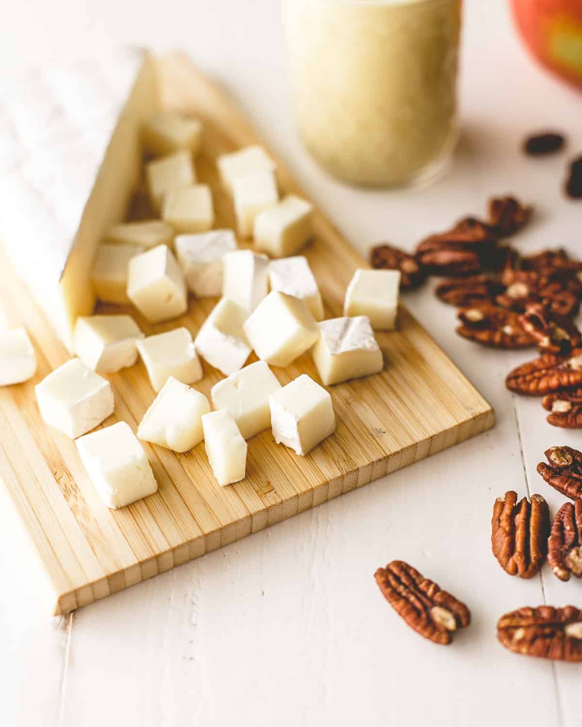 brie cubes and pecans on a white table