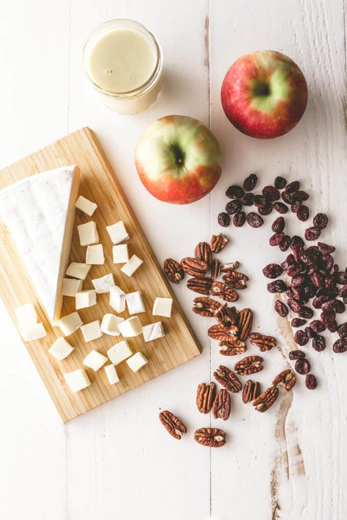 brie, apples and pecans on a white table