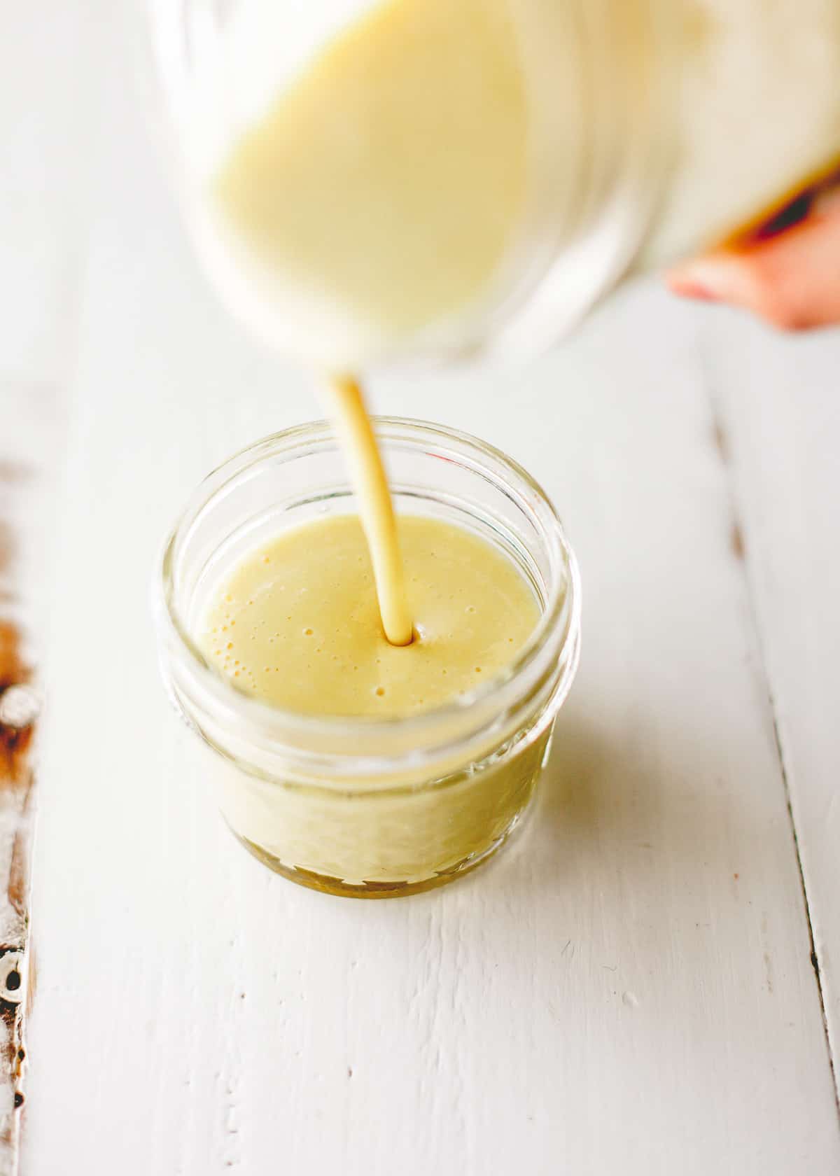 pouring vinaigrette in a glass jar