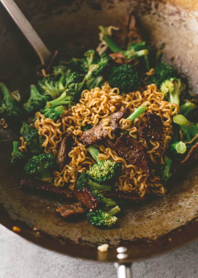 mixing steak and cooked broccoli in a wok
