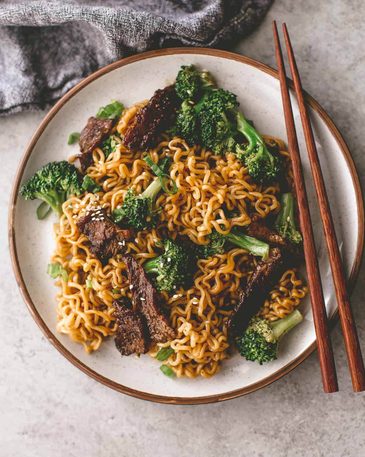 beef and broccoli stir fry on a white plate with chopsticks