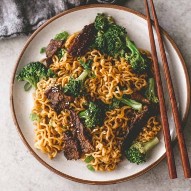 beef and broccoli stir fry on a white plate with chopsticks
