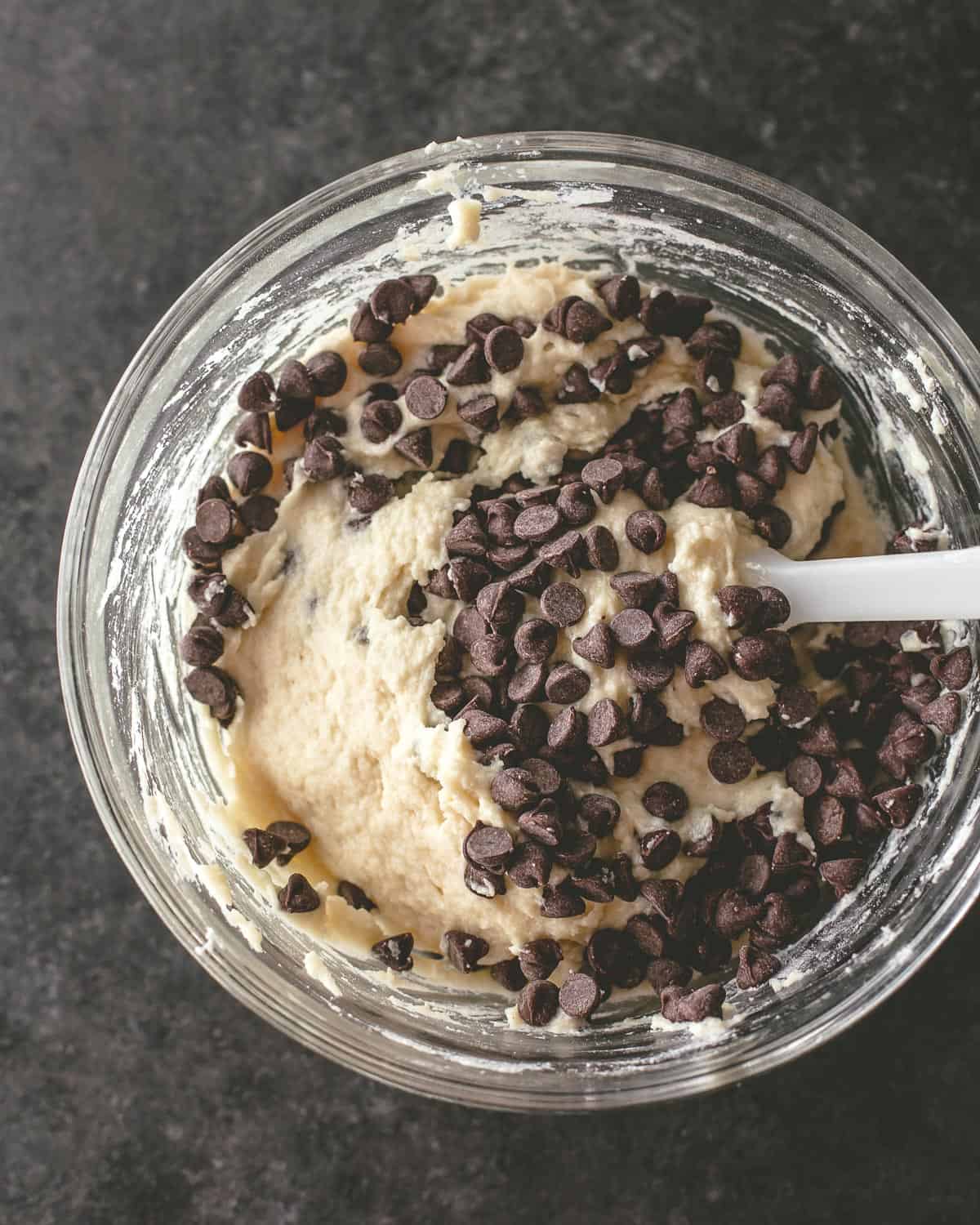 overhead image of a spatula mixing chocolate chips into cake batter