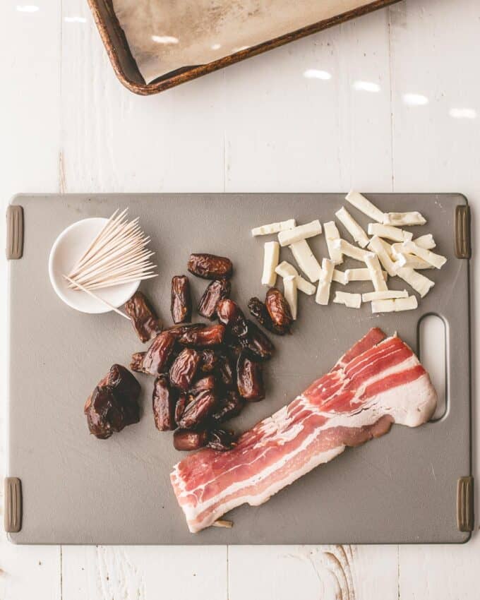 ingredients for bacon wrapped dates on a grey cutting board