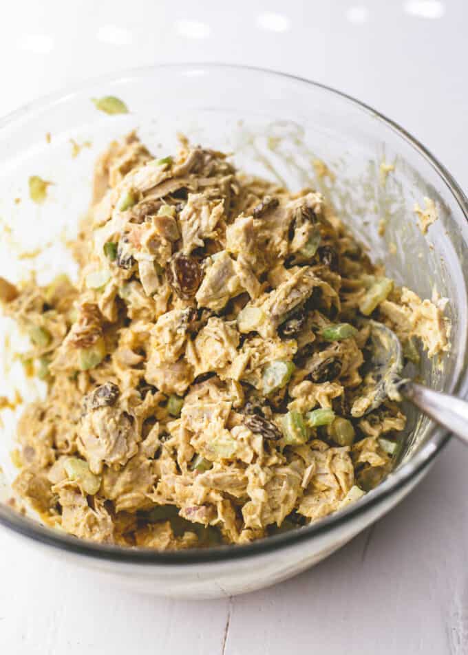 curried turkey salad in a clear bowl with a spoon