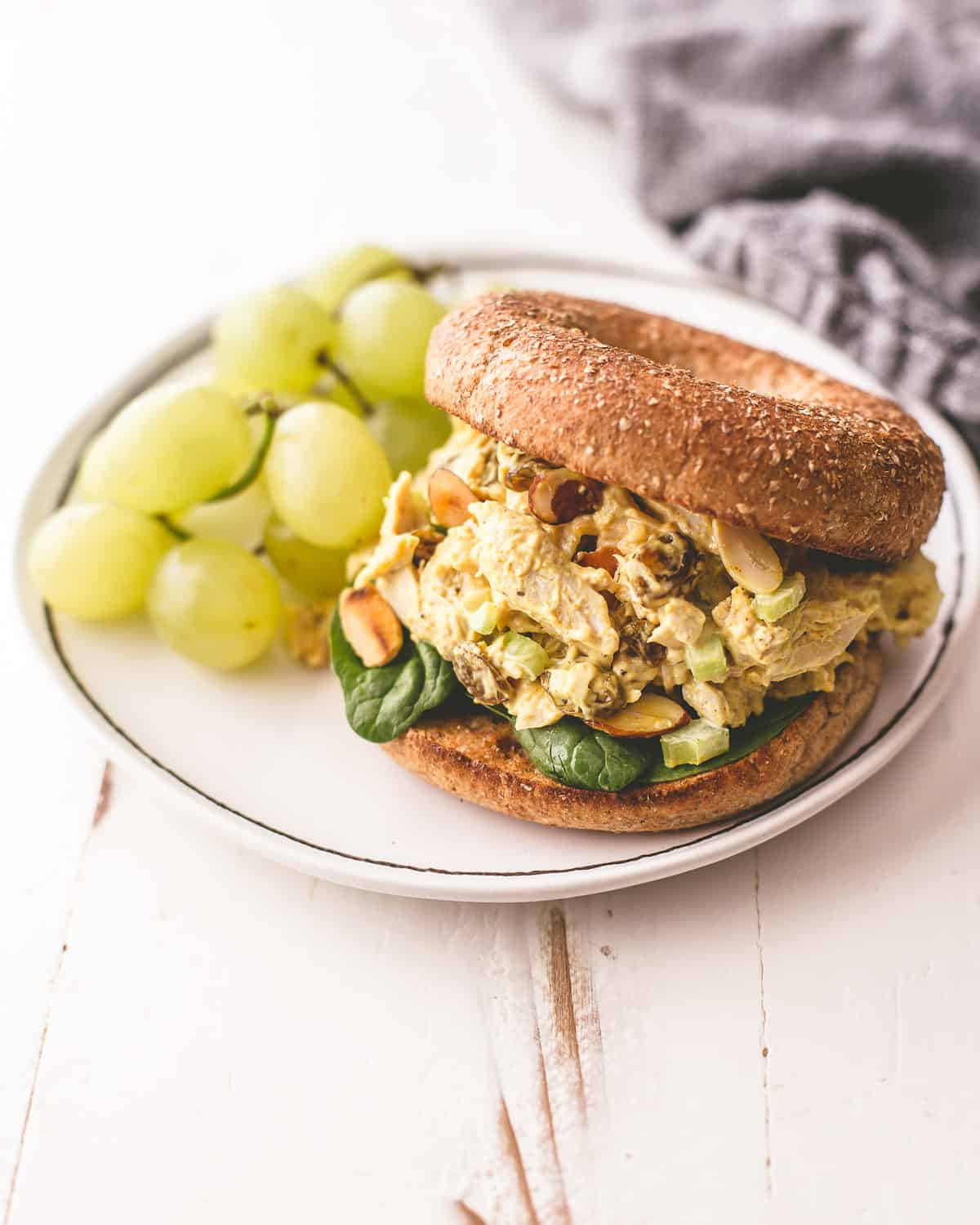 curried turkey salad sandwich on a white plate with green grapes