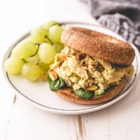 curried turkey salad sandwich on a white plate with green grapes
