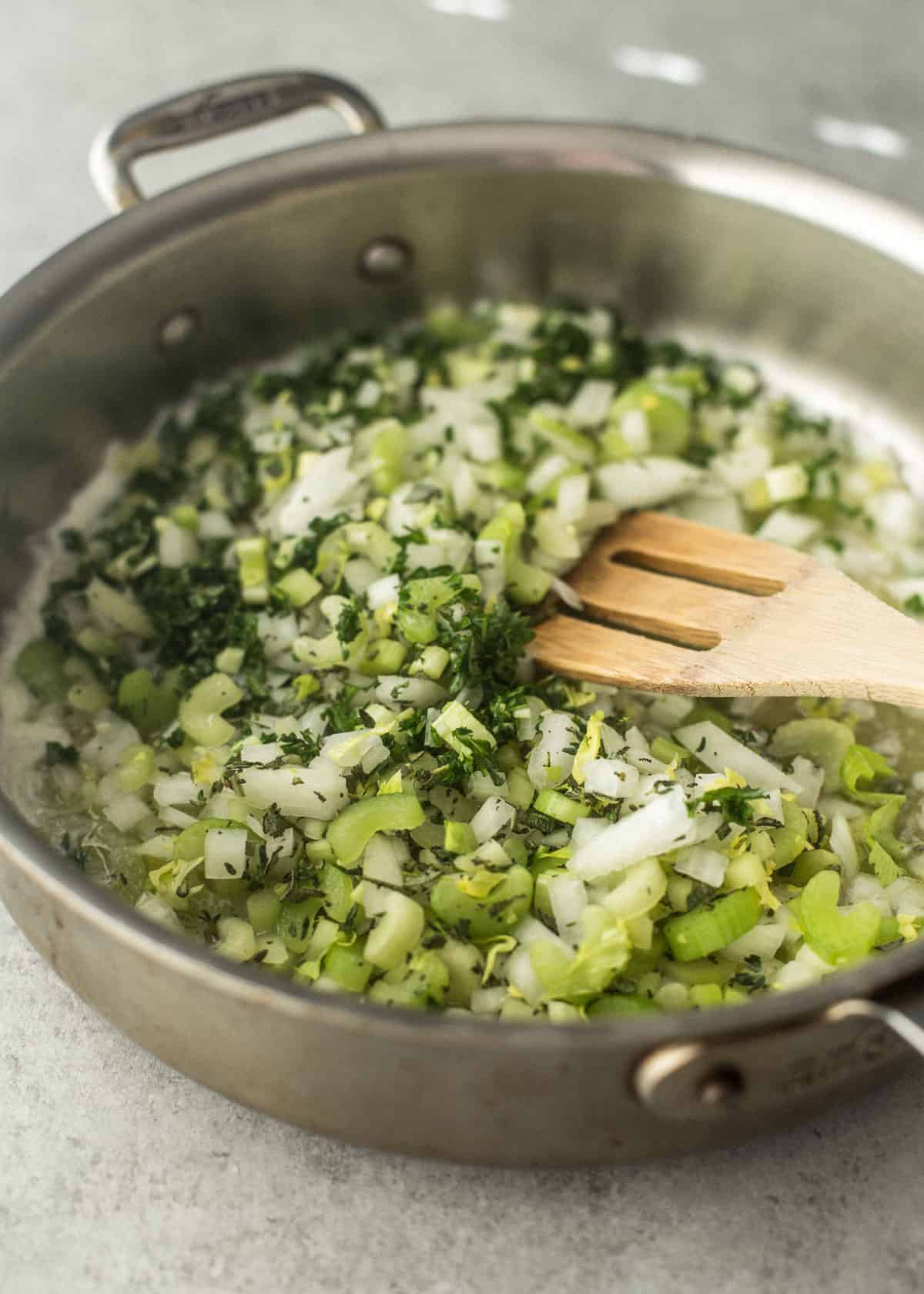 stirring celery, herbs and onion in a skillet
