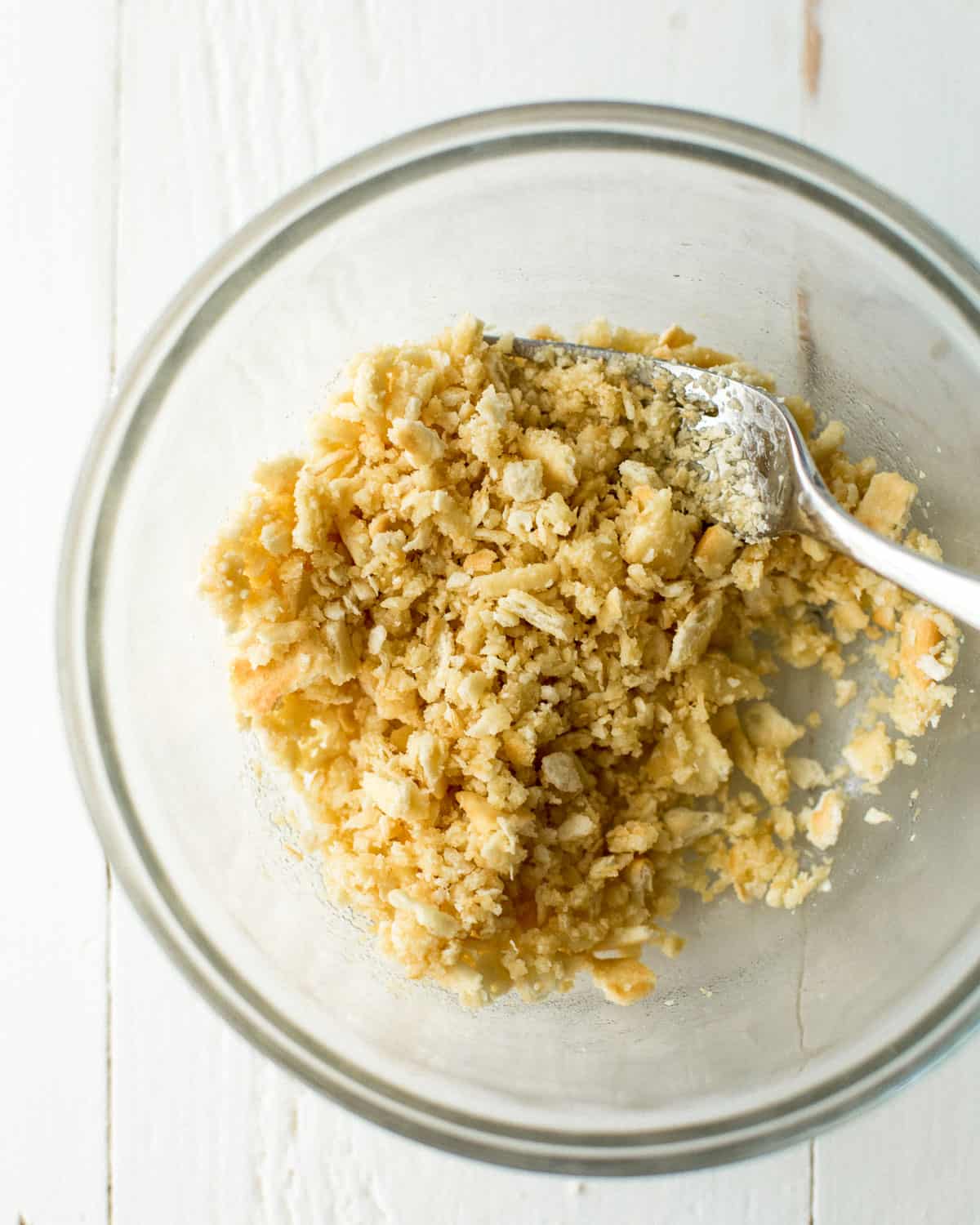 overhead image of crushing ritz crackers in a clear bowl