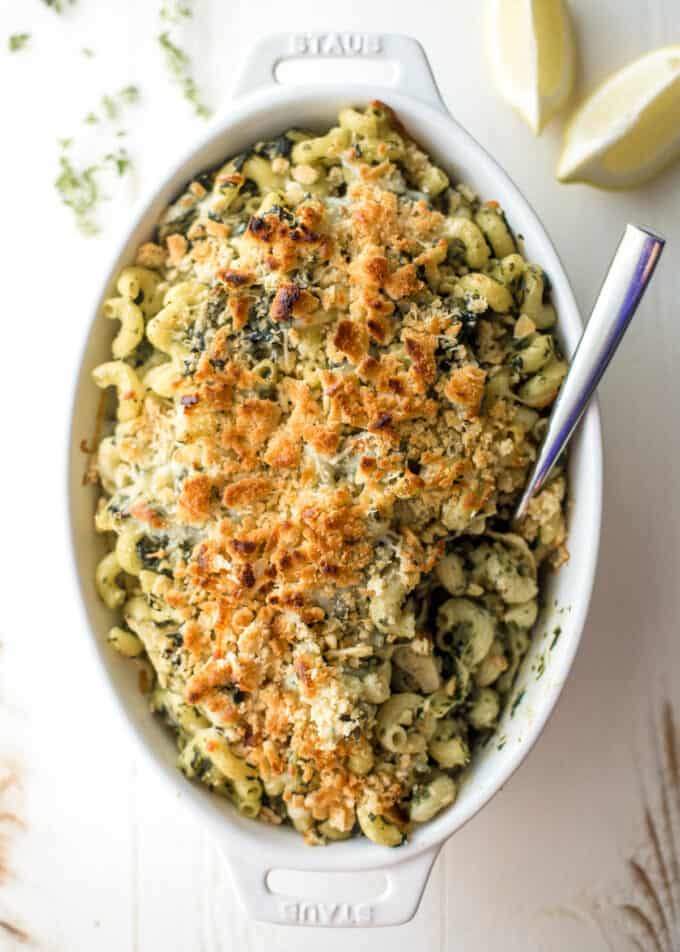 spinach and artichoke baked pasta in a white oval baking dish