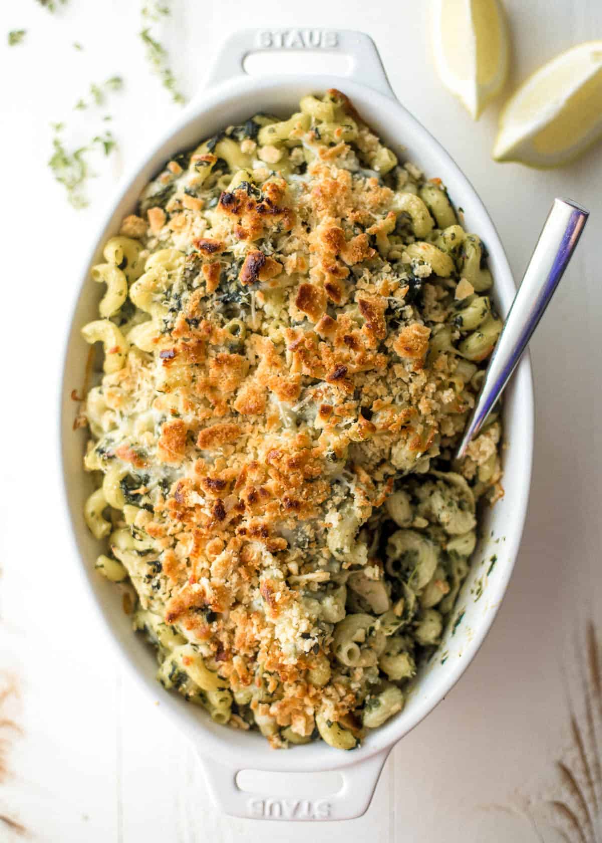 overhead image of spinach and artichoke baked pasta in a white oval baking dish