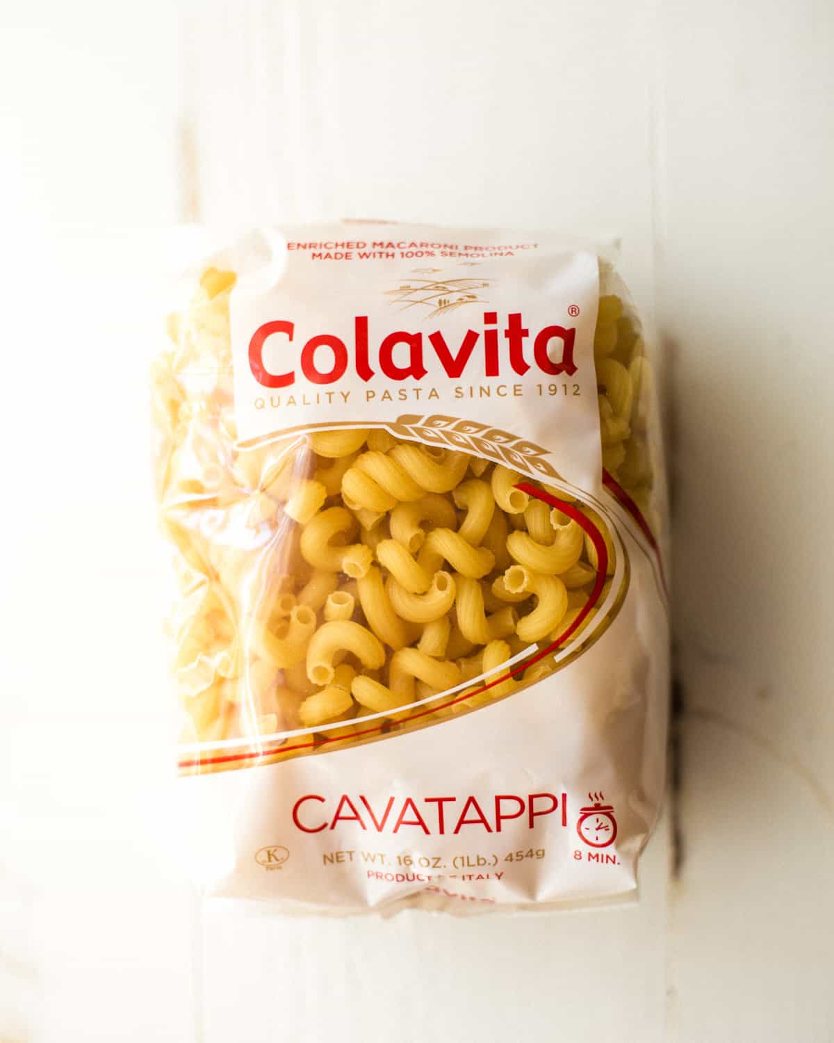 overhead image of a bag of spiral pasta on a white background