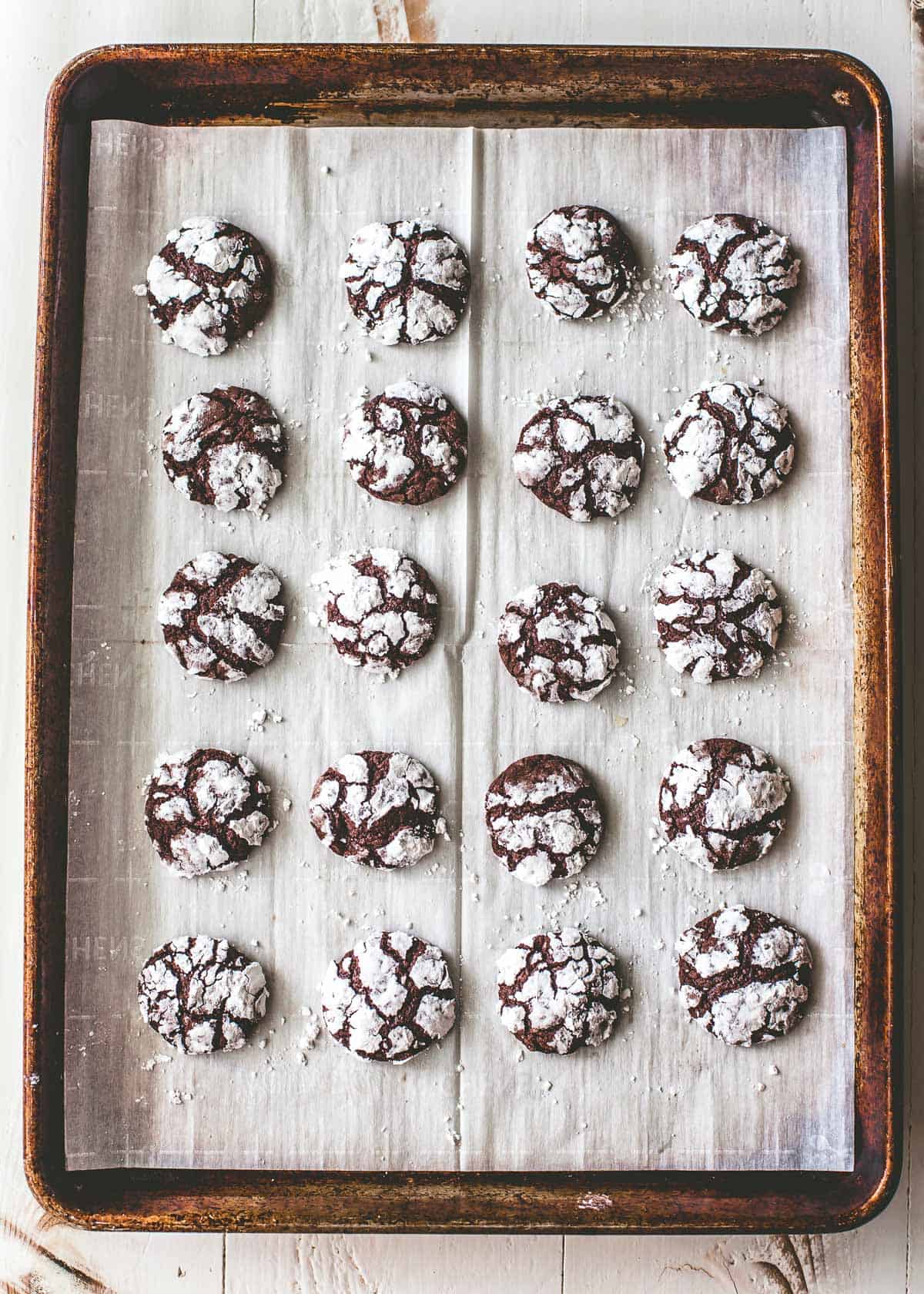 chocolate brownie crackle cookies on a parchment lined sheet pan