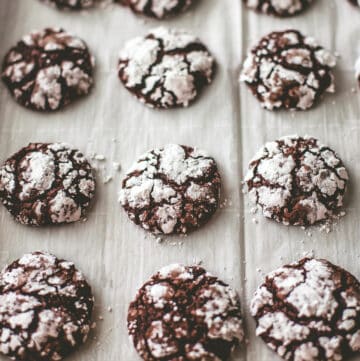 chocolate brownie crackle cookies on a parchment lined sheet pan