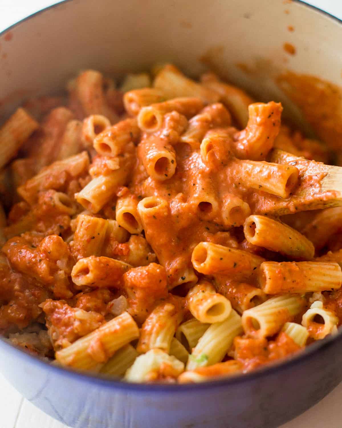 overhead image of stirring pasta into tomato sauce