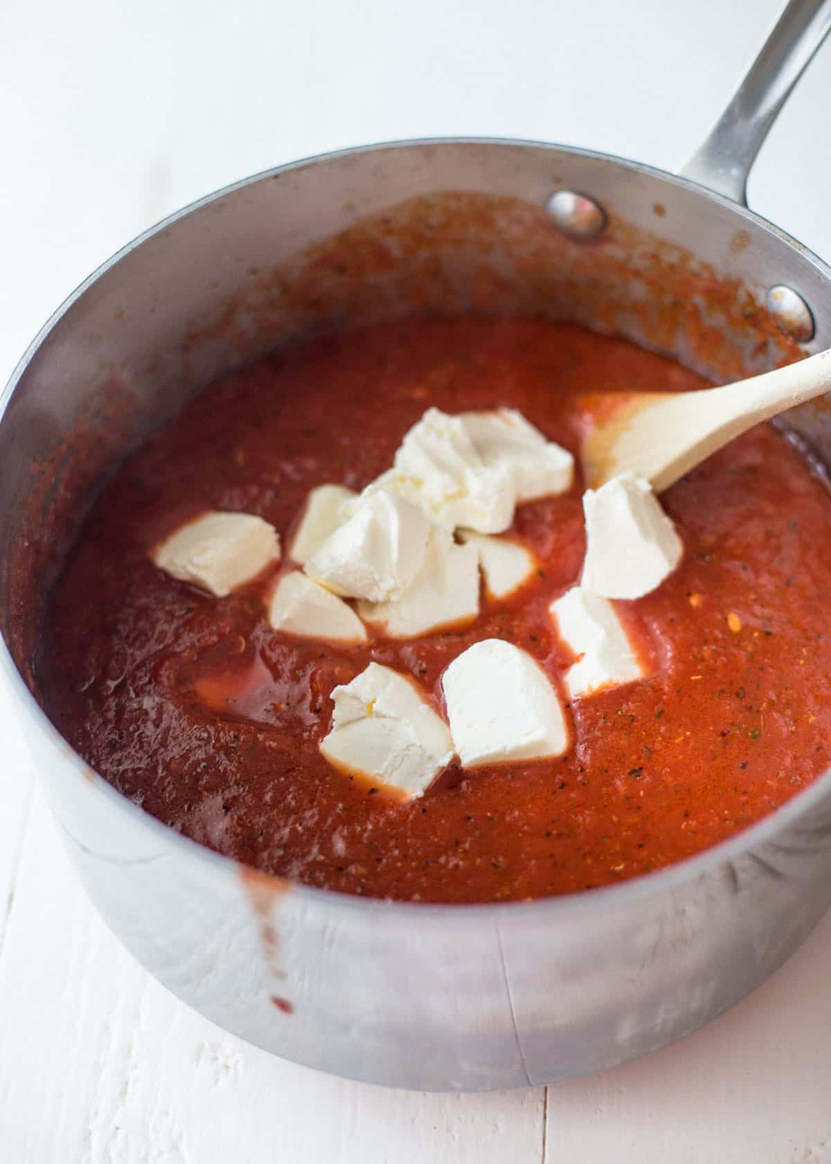 adding cream cheese to tomato sauce