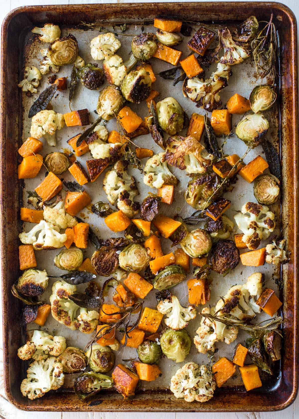 overhead image of herb roasted vegetables on a sheet pan