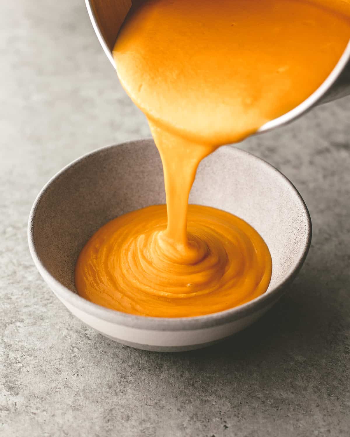 pouring soup into a white bowl