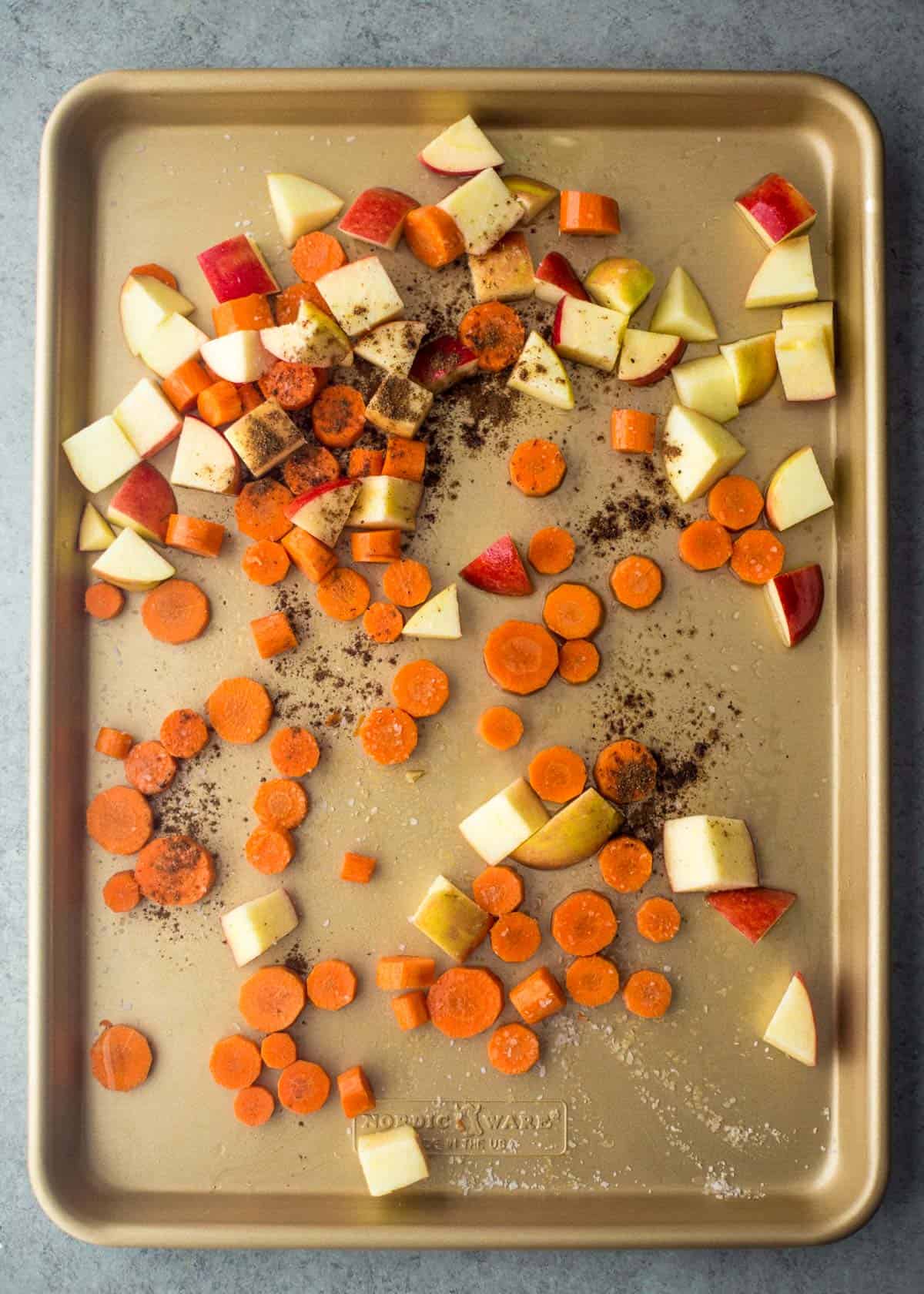 overhead image of diced raw apples and carrots on a sheet pan