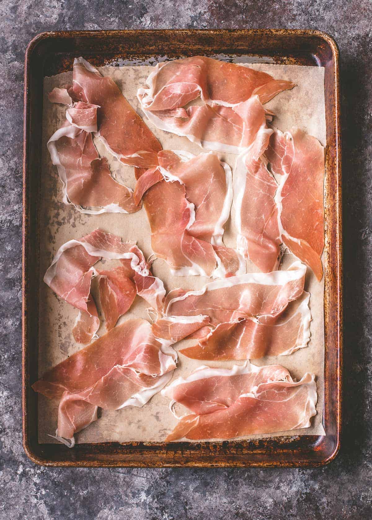 overhead image of uncooked prosciutto on a sheet pan