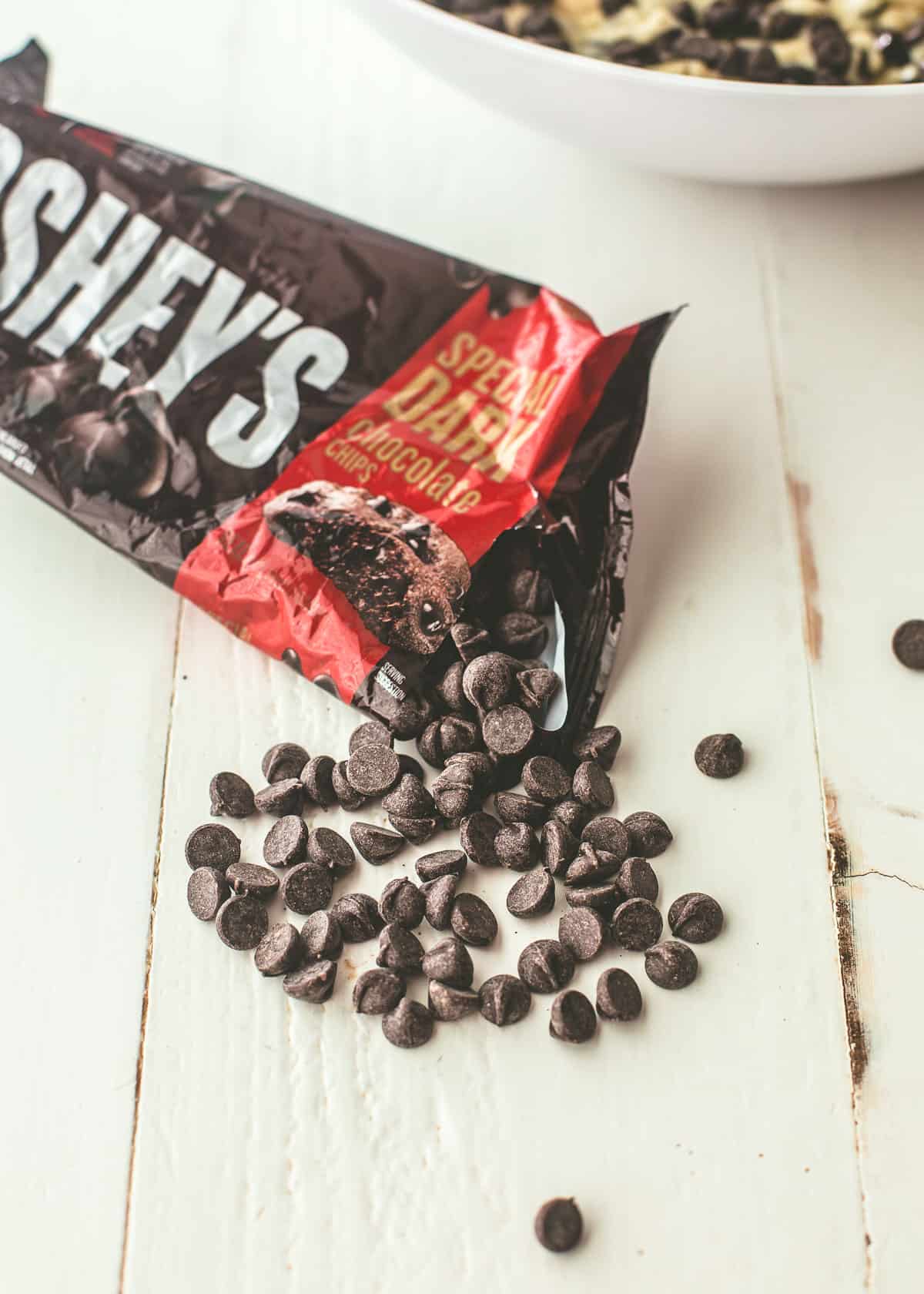 chocolate chips spilling out of a package on a white table