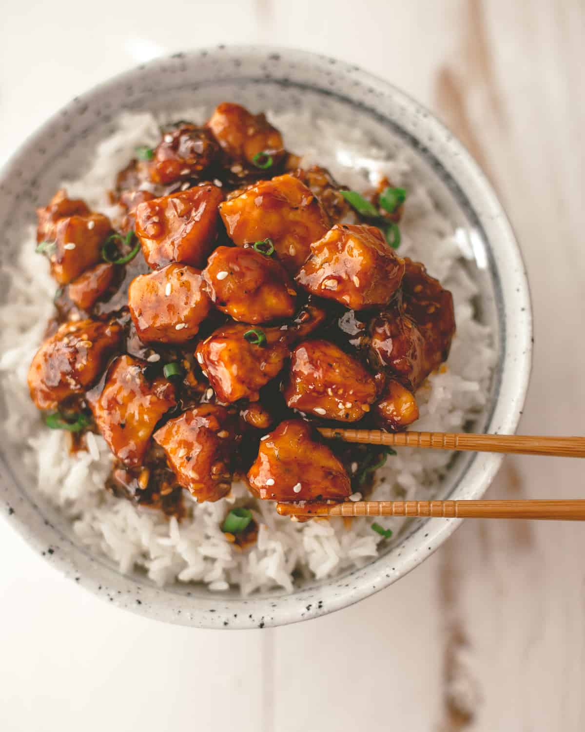 chicken stir fry over rice in a white bowl