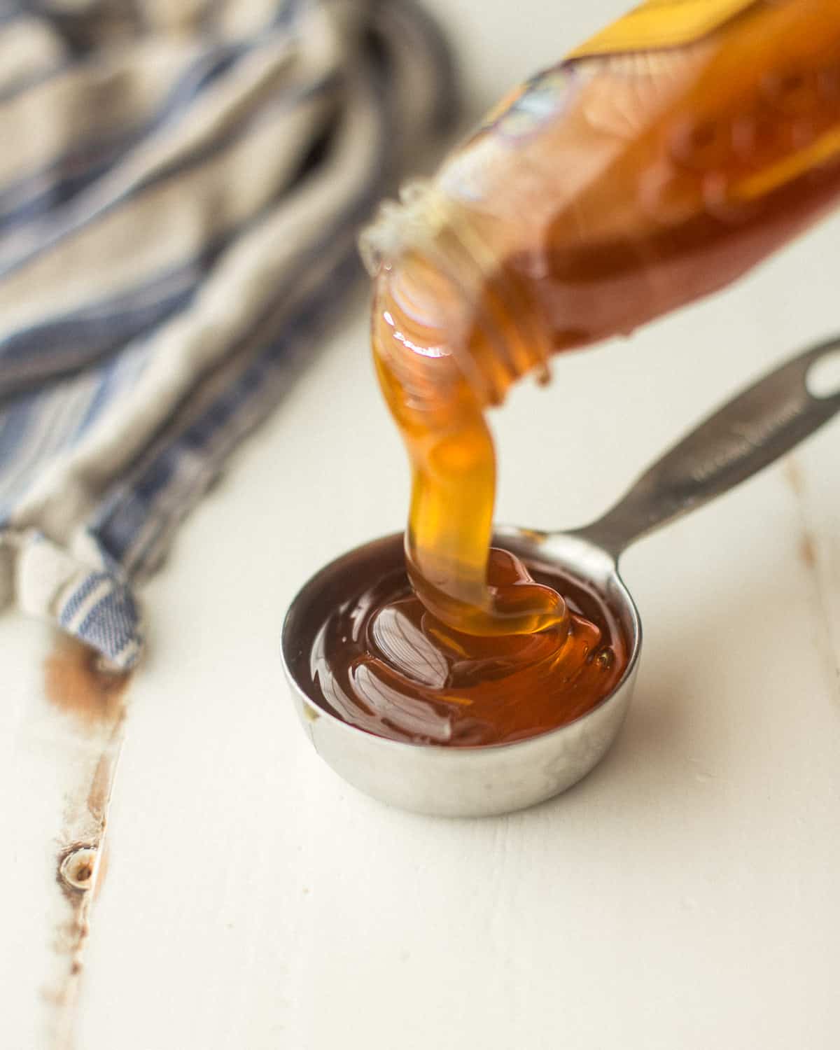 pouring honey into a metal measuring cup