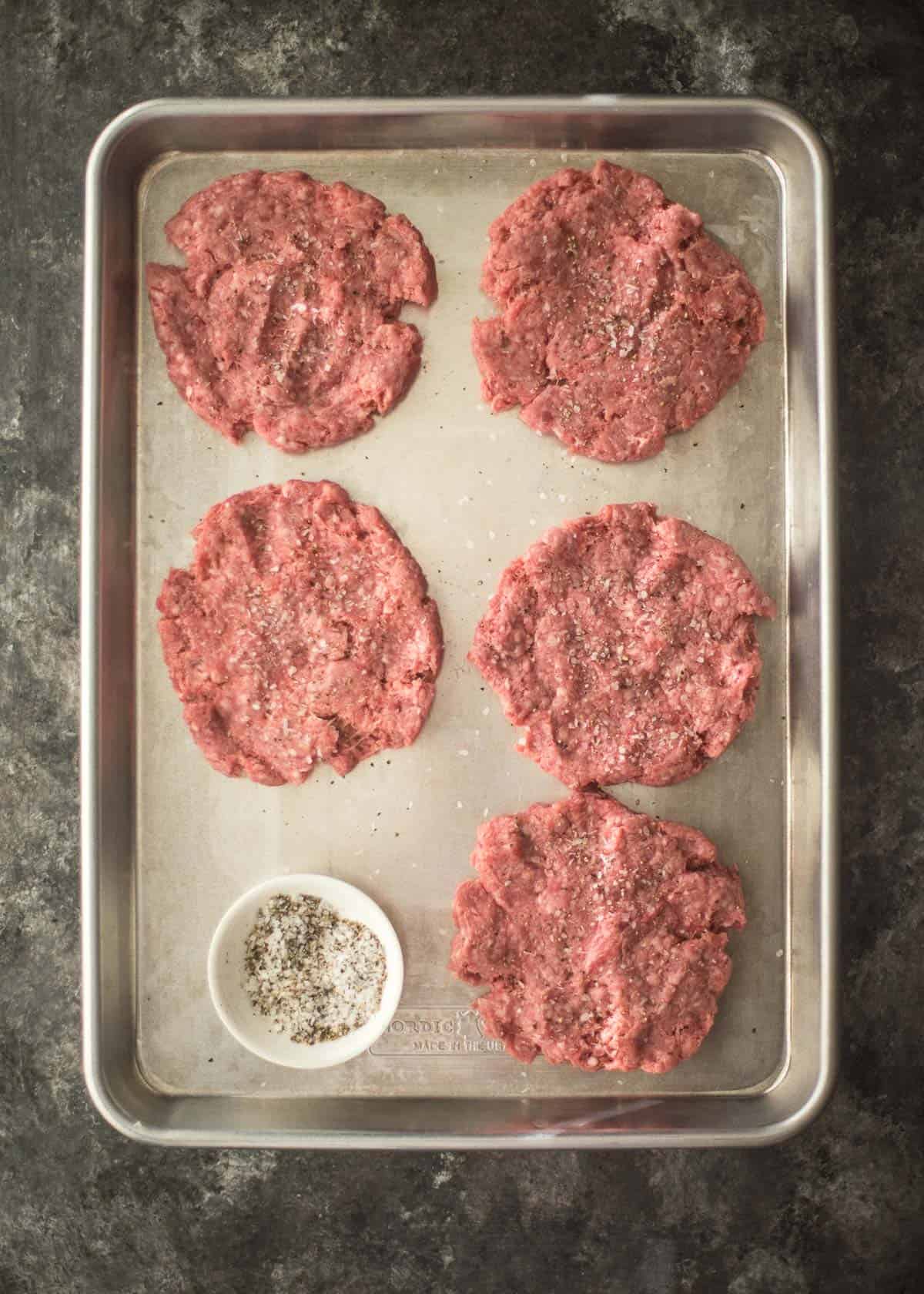overhead image of raw hamburger patties on a sheet pan