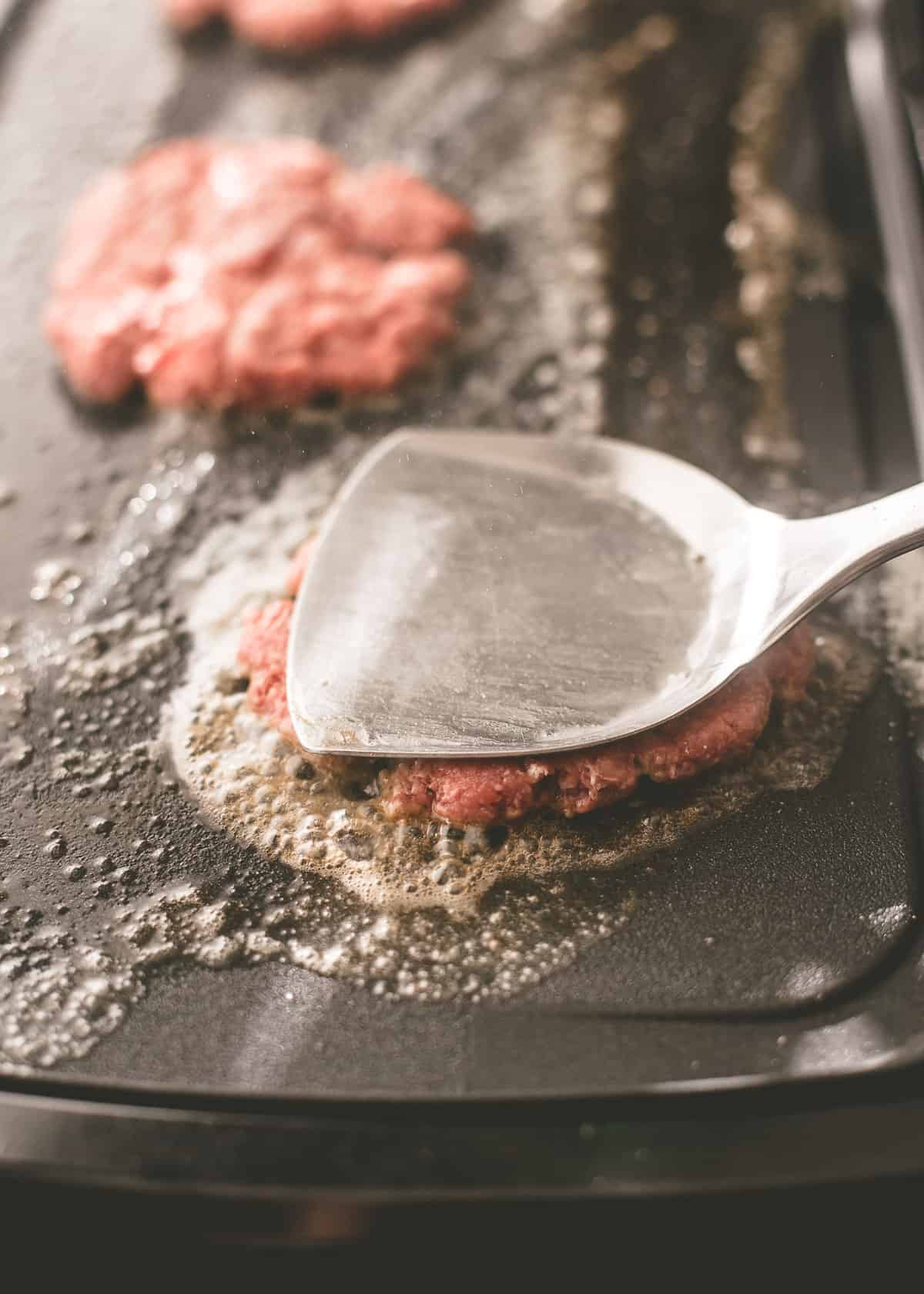 flattening burgers with a spatula
