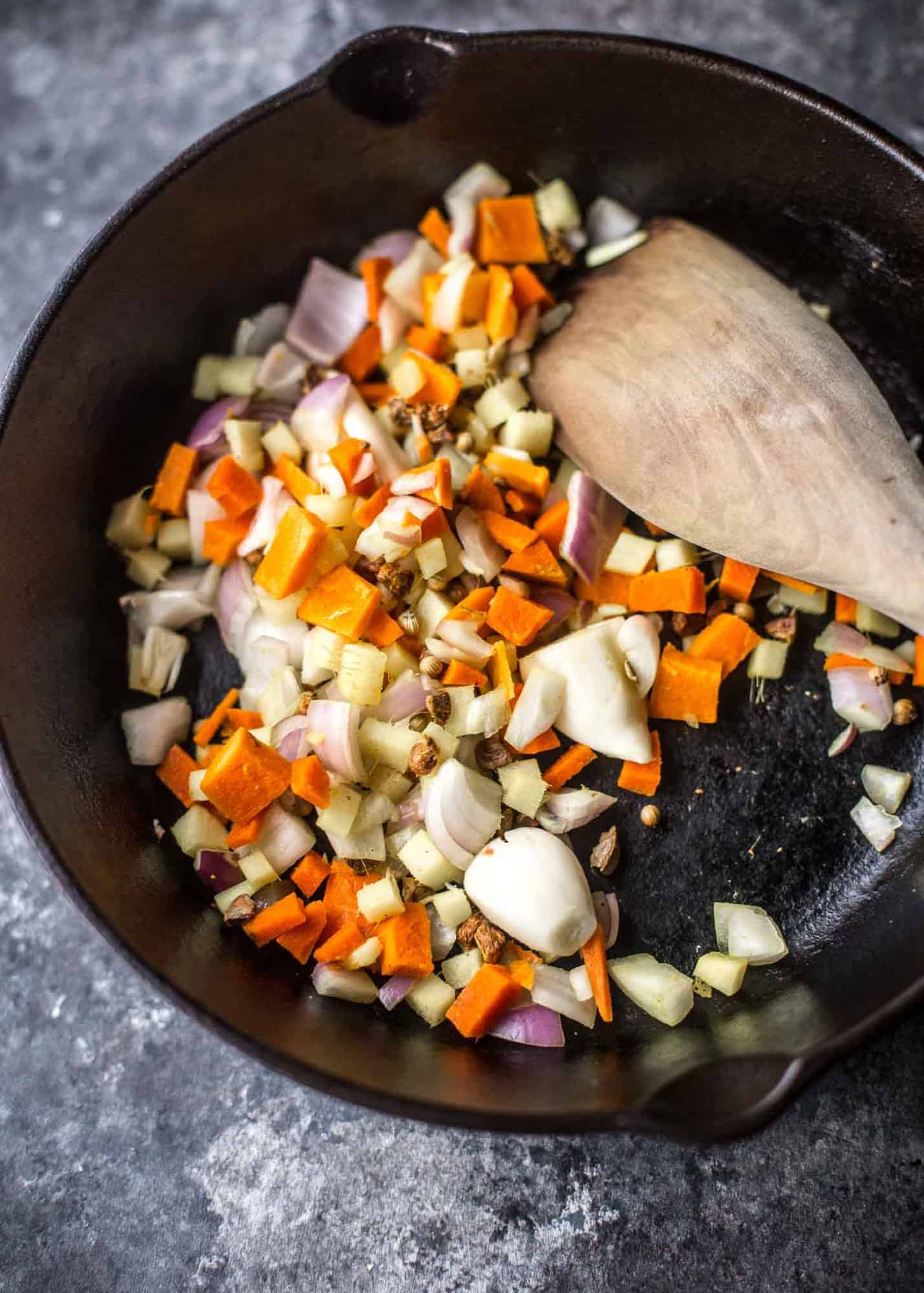 stirring vegetables in a cast iron skillet