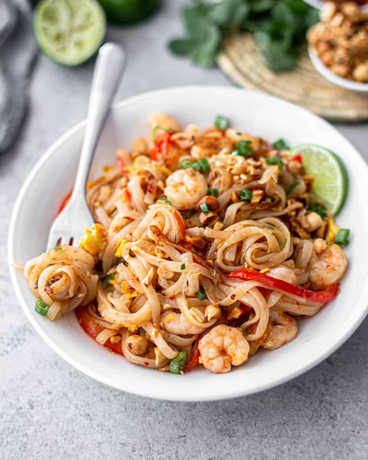 pad thai in a white bowl with a fork