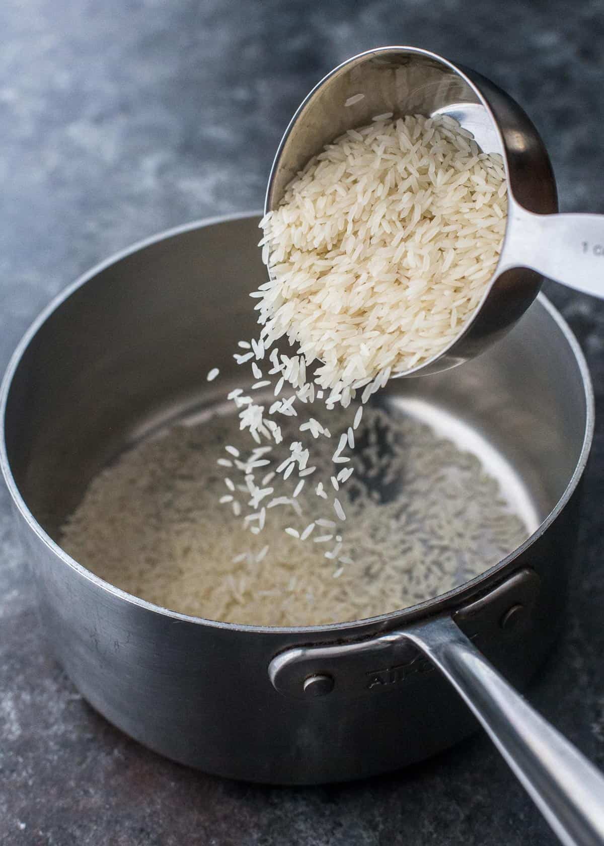 adding rice to a saucepan