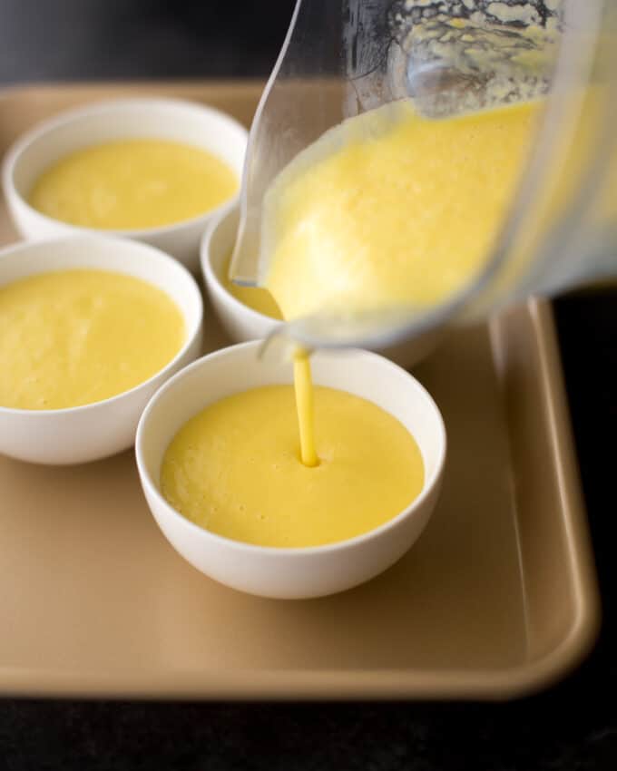 pouring mango pudding mixture into white bowls