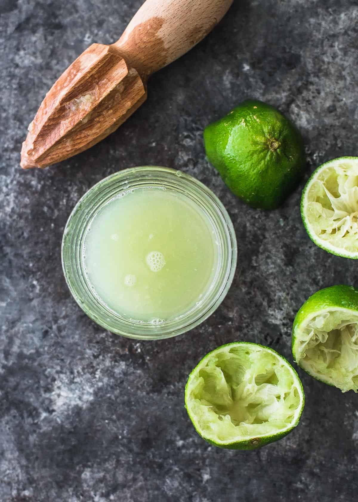 overhead image of limes and lime juice on a grey countertop