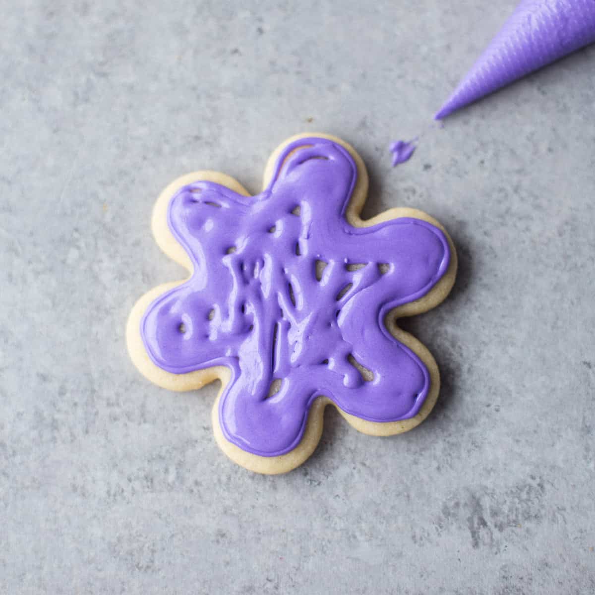 adding purple icing to a sugar cookie