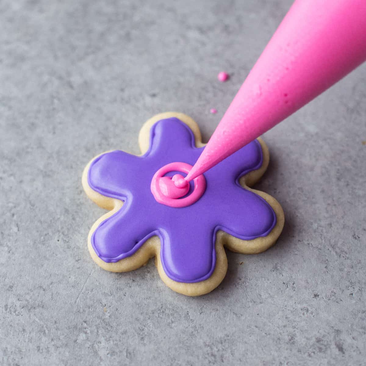 icing a flower-shaped sugar cookie