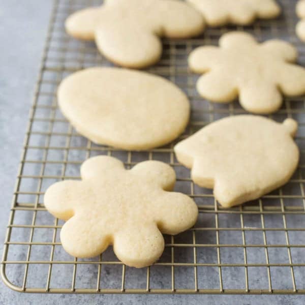 unfrosted sugar cookies in the shape of flowers on a cooling rack