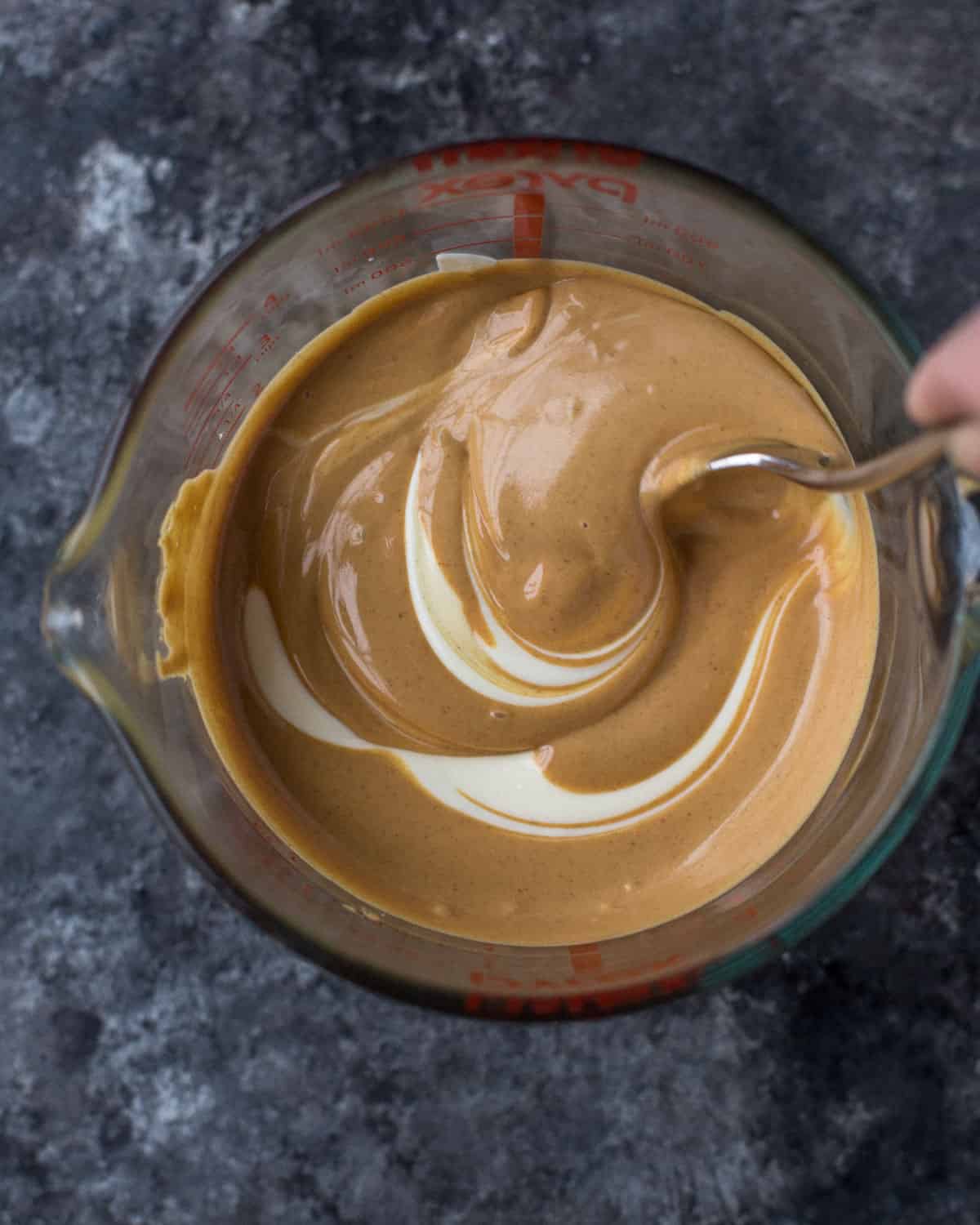 stirring peanut butter and white chocolate in a clear bowl